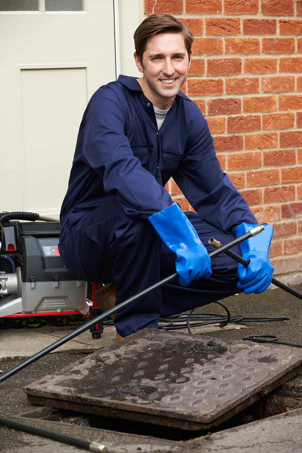 A man cleaning a main drain