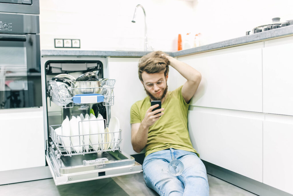 Man does housework in the kitchen, loads the dishes in the dishwasher