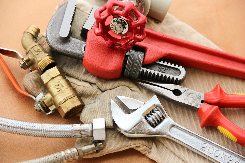 An adjustable wrench, a pipe wrench, a pair of pliers, and a pipe