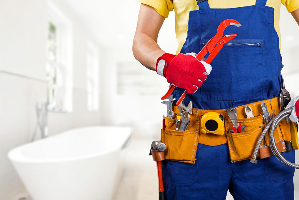 Torso of a plumber wearing overalls and a tool belt