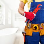 Torso of a plumber wearing overalls and a tool belt