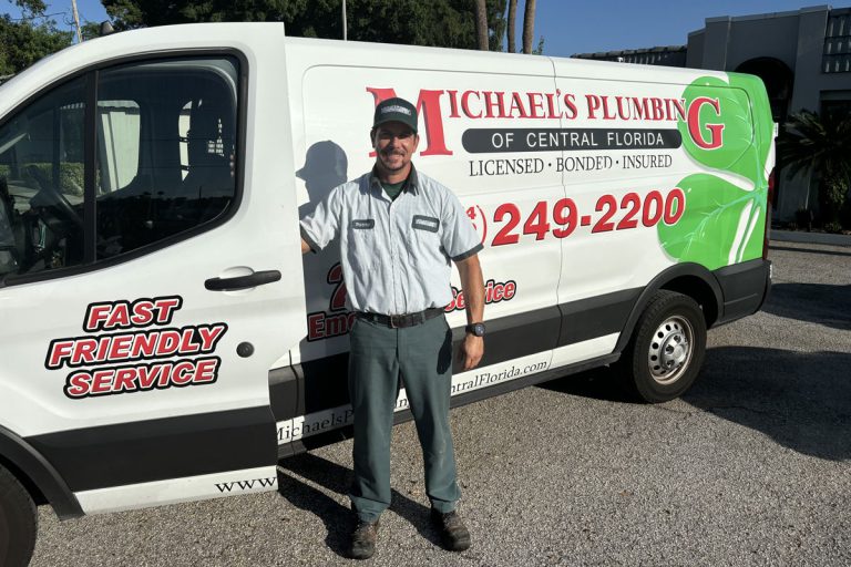 Plumber standing next to a Michael's Plumbing service van