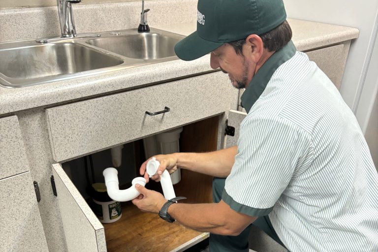 Plumber repairing pipes under a kitchen sink