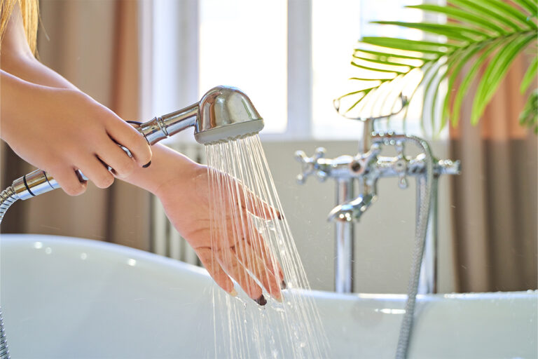 Woman checks the temperature of the water in the background of the bathroom
