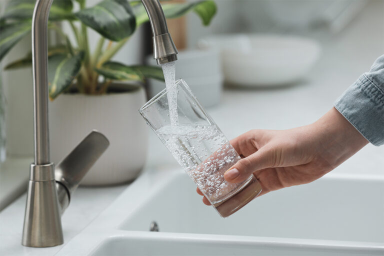 Close-up of woman filling glass with water from tap in kitchen
